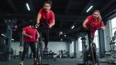 Grup atletik kızlar spor salonunda bisiklet sürme egzersizleri yapıyorlar.