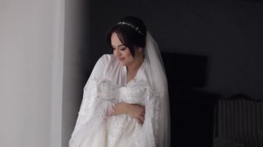 Gelinliği, gelinliği, pencerenin yanındaki gelinliği, beyaz elbisesi ve duvağıyla duruyormuş.