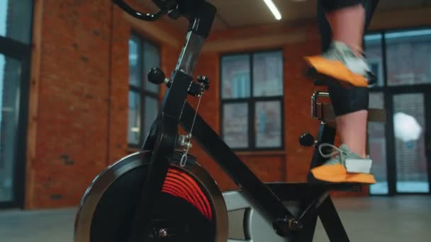 Mulher caucasiana saudável exercitando exercício na bicicleta estacionária da máquina de ciclismo no ginásio, câmera lenta — Vídeo de Stock