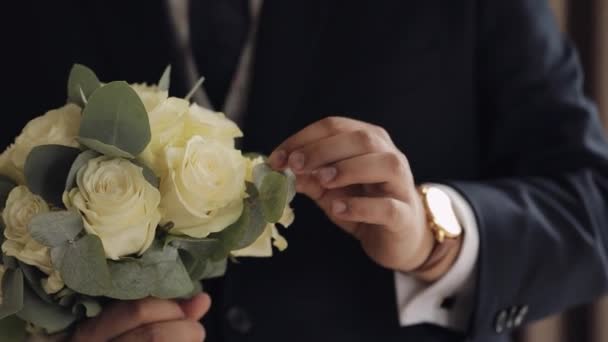 Brudgum med bröllopsbukett i händerna hemma förbereder sig för att gå till bruden, närbild slow motion — Stockvideo