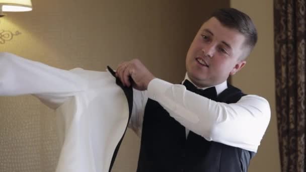 Handsome stylish groom man wearing white jacket at home in living room, slow motion indoors portrait — Stockvideo