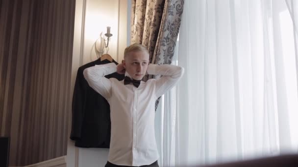 El novio ajusta la corbata de lazo, preparándose para ir a la novia, hombre de negocios con camisa blanca, día de la boda — Vídeo de stock