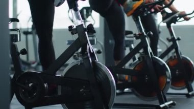 Sağlıklı bir beyaz kadın grubu spor salonunda sabit bisiklet üzerinde egzersiz yapıyor.