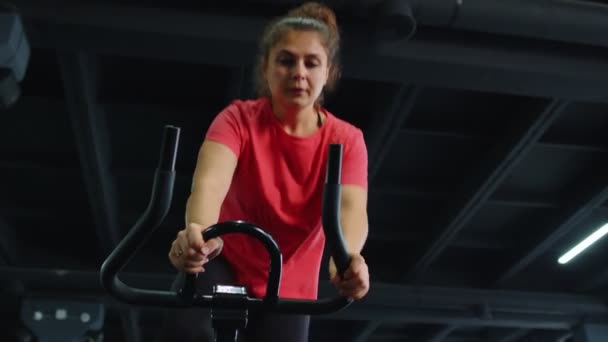 Meisjesgroep voert aerobische training cardio routine uit op fietssimulatoren, fietstraining — Stockvideo