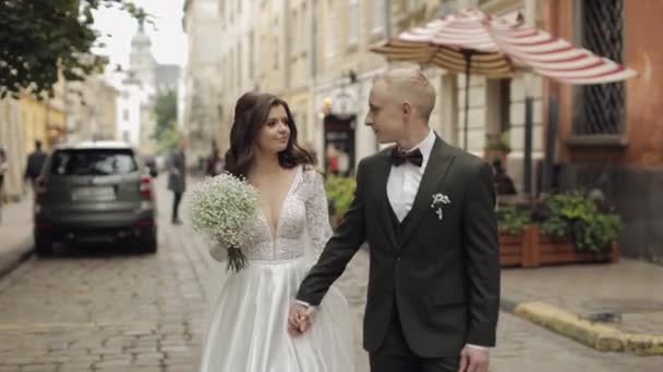 Yeni evlilerin portresi, beyaz gelinin yürüyüşü, kucaklaşması, şehir caddesinde sarılması, düğün çifti. — Stok video