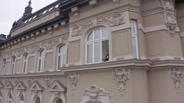 Αεροφωτογραφία του κομψού γαμπρού άντρας διαμονή στο παράθυρο στο σπίτι ετοιμάζεται πριν από την ημερομηνία ή συνάντηση με τη νύφη — Αρχείο Βίντεο