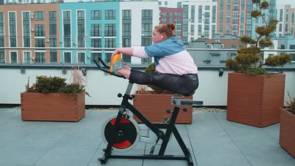 Caucasian woman coach making stretching aerobic training exercises on stationary bike outdoors — стокове відео