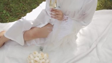 Gelinin gelinliği sabah bahçesinde oturmuş geceliğiyle şampanya içen kadın.