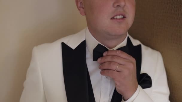 A vőlegény igazítja a csokornyakkendőt, készül a menyasszonyhoz, üzletember fehér ingben, esküvő napján — Stock videók
