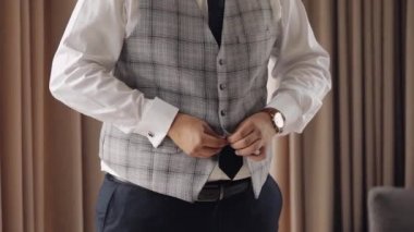 Düğmeli ceket, elleri kapalı, takım elbiseli adam ceketinin düğmelerini bağlıyor ve dışarı çıkmaya hazırlanıyor.