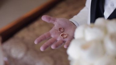 Gri ceketli damat avucunun içinde alyansları tutuyordu. Yumruğunda yüzükler vardı.