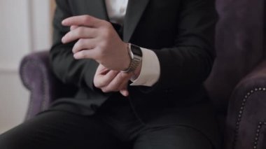 Adam kol saati takıyor, damat elbisesi giyiyor, erkek işadamı buluşmayı bekliyor, saatle el ele.