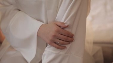 Hand with engagement ring close-up wedding bride in night gown and veil sitting at home room