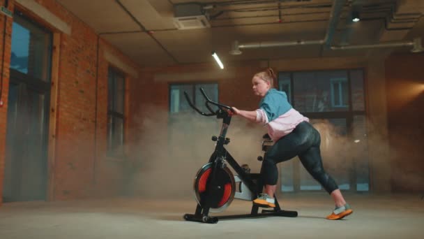 Atletische vrouw rijden op spinnen stationaire fiets training routine in nevel sportschool, gewichtsverlies binnen — Stockvideo