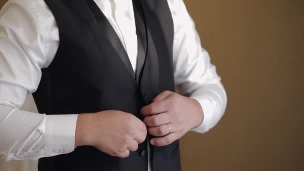Піджак для кнопок для нареченого, чоловік у костюмі застібає кнопки на піджаку, готуючись вийти — стокове відео