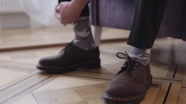 Close-up hands of man groom adjusting, wearing, putting his wedding shoes in hotel room near window — Stock Video