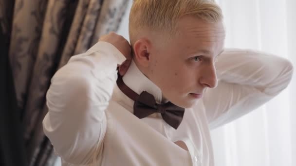 Homem de noivo ajusta gravata borboleta, preparando-se para ir para a noiva, homem de negócios em camisa branca, dia do casamento — Vídeo de Stock