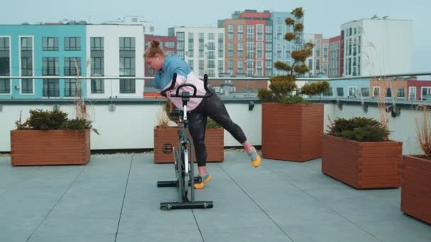 Athletic girl make acrobatic trick on bike exercising workout on stationary cycling machine outdoors — Vídeo de Stock