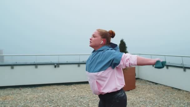 Menina desportiva em sportswear faz ioga alongamento exercício usando elástico no telhado da casa ao ar livre — Vídeo de Stock