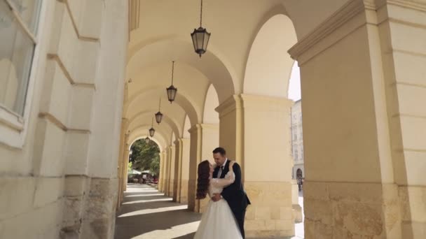 Newlyweds portrait, caucasian groom bride hugging, embracing, kissing on city street, wedding couple — стоковое видео