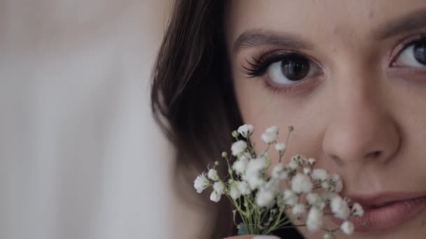 Zbliżenie piękny piękny twarz panna młoda dziewczyna patrząc w aparat i uśmiechając się z kwiaty bukiet — Wideo stockowe