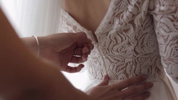 Cravatte damigella d'onore e aiuta a mettere su abito da sposa, preparazione del mattino della sposa con abito bianco — Video Stock