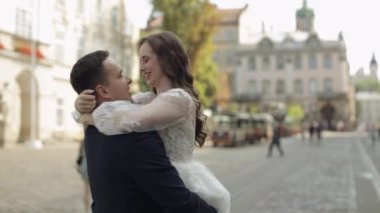 Newlyweds portrait, caucasian groom bride dancing, embracing, hugs on city street, wedding couple