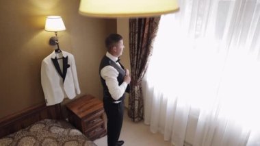 Damat ceketi, takım elbiseli adam ceketinin düğmelerini bağlar ve dışarı çıkmaya hazırlanır.
