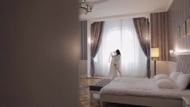 Gelinliği, gelinliği, pencerenin yanındaki gelinliği, beyaz elbisesi ve duvağıyla duruyormuş.