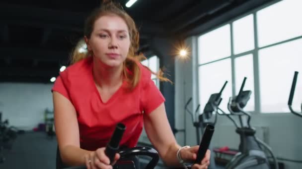 Woman performs aerobic endurance training workout cardio routine on the simulators, cycle training — Stockvideo