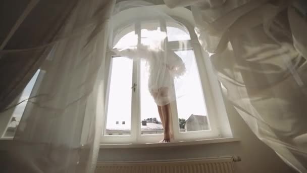 Bruid in boudoir jurk verblijf op vensterbank bruiloft ochtend voorbereidingen vrouw in nachtjapon, sluier — Stockvideo