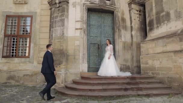 Recién casados, novio caucásico con novia caminando, abrazando, abrazos en la calle de la ciudad, pareja de bodas — Vídeo de stock