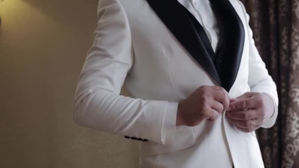 Groom buttoning jacket, man in suit fastens buttons on his jacket preparing to go out — Stockvideo
