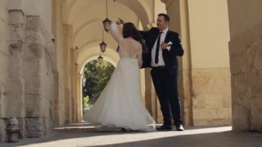 Newlyweds portrait, caucasian groom bride dancing, embracing, hugs on city street, wedding couple
