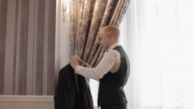 Evde yeşil ceketli yakışıklı damat, oturma odasında ağır çekimde kapalı mekan portresi.