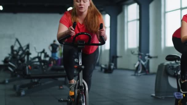 Groep van lachende vrienden vrouwen klasse te oefenen, training, spinnen op stationaire fiets in de moderne sportschool — Stockvideo