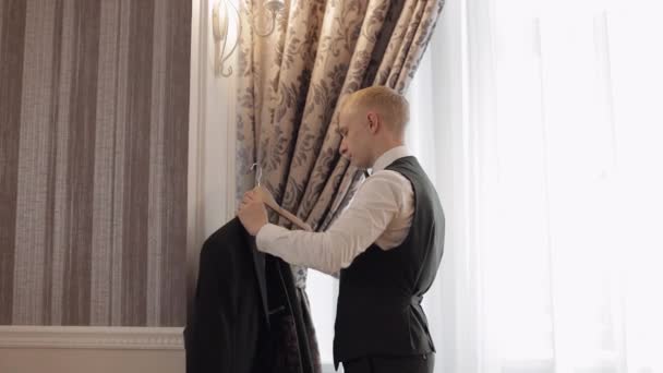 Mooie stijlvolle bruidegom man draagt groene jas thuis in de woonkamer, slow motion binnenportret — Stockvideo