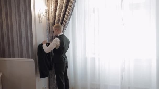 Snygg snygg brudgum man bär grön jacka hemma i vardagsrummet, slow motion inomhus porträtt — Stockvideo