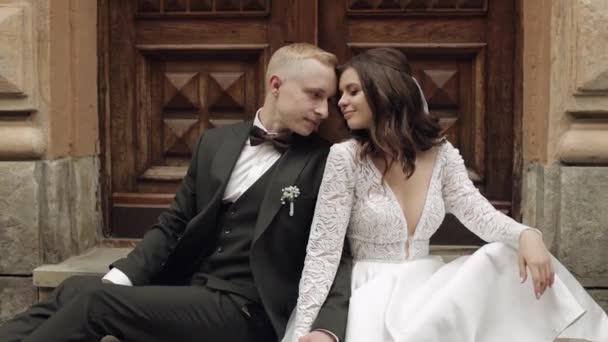 Newlyweds love, caucasian groom with bride sitting, embracing, hugs in city street, wedding couple — Vídeo de Stock