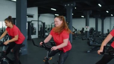 Grup atletik kızlar spor salonunda bisiklet sürme egzersizleri yapıyorlar.