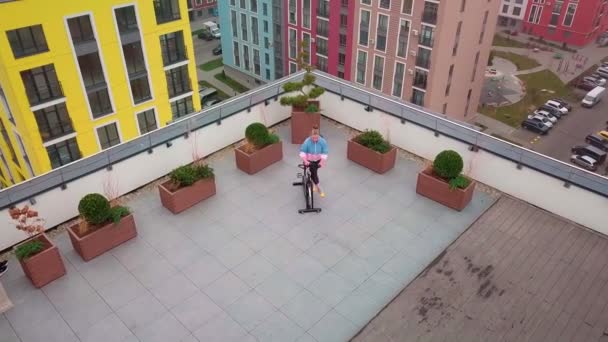 Healthy Caucasian woman exercising workout on stationary cycling machine bike on house rooftop gym — Stockvideo