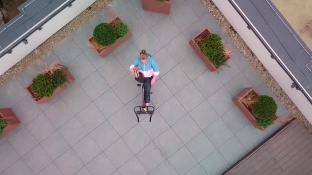 Athletic woman makes twine training routine on spinning stationary bike on house roof, weight loss — Stockvideo