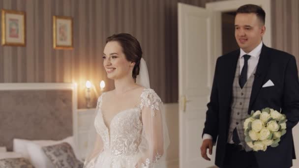Молодые кавказские невеста и жених впервые встречаются на свадьбе, целуются в помещении — стоковое видео
