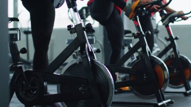 Sağlıklı bir beyaz kadın grubu spor salonunda sabit bisiklet üzerinde egzersiz yapıyor.