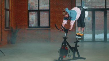 Kadın, simülatörlerde aerobik dayanıklılık antrenmanı, kardiyo çalışması ve bisiklet eğitimi yapıyor.