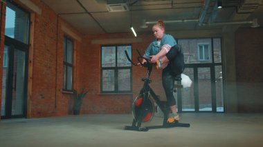 Kadın, simülatörlerde aerobik dayanıklılık antrenmanı, kardiyo çalışması ve bisiklet eğitimi yapıyor.