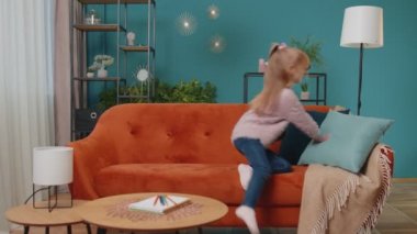 Küçük ilkokul çocuğu cep telefonu teknolojisi kullanıyor evde tek başına kanepede oturuyor.