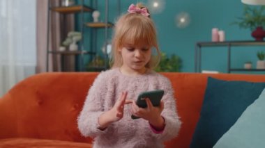 Heyecanlı kazanan kız cep telefonu kullanıyor ve evet diyor evde tek başına sürpriz bir şekilde el kaldırıyor.