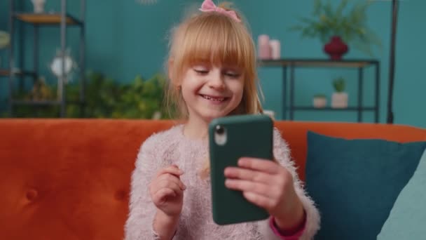 Barn småbarn hålla smartphone titta på roliga karikatyrer, chatta med vänner på soffan ensam hemma — Stockvideo