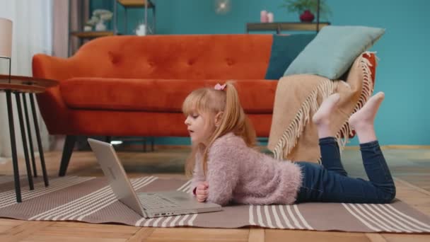 Niña de la escuela pequeña uso ordenador portátil aprendizaje lectura lecciones de educación en línea solo en casa — Vídeo de stock